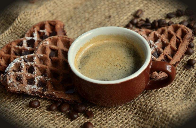 heart-shaped waffles, a cup of coffee, coffee beans