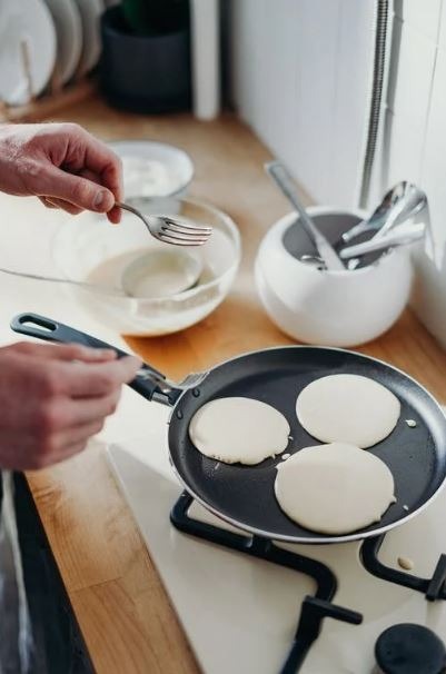Man pours pancake batter onto a skillet