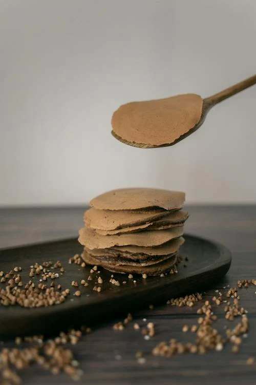 Unrecognizable cook serving buckwheat pancakes on a plate