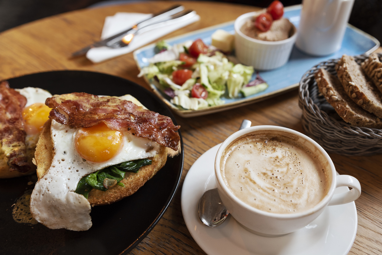 Fried egg with bacon on a plate, salad and coffee cup