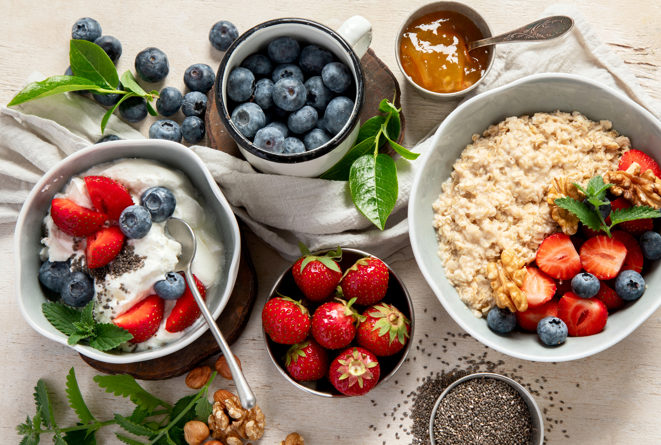 Organic ingredients for healthy breakfast - yoghurt, nuts, fresh fruits, oatmeal, whole grain flakes on white background. Top view