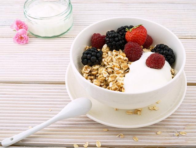yogurt with fruits in a bowl, nuts, raspberries, oats