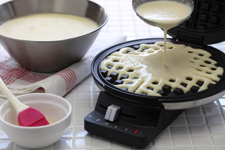 preparing homemade waffles by waffle maker machine.