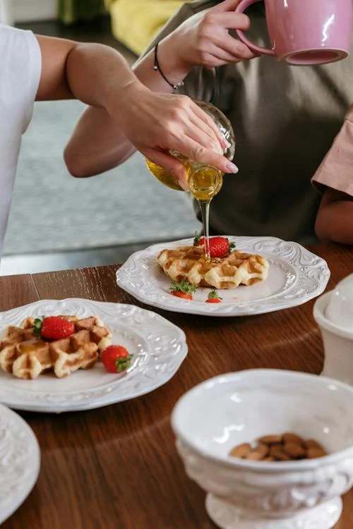 Person pouring syrup on waffle